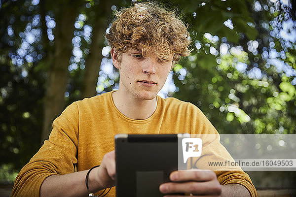 Portrait of young man using digital tablet outdoors
