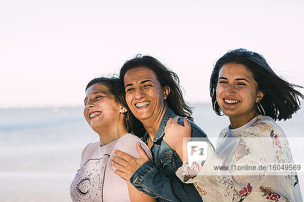 Happy mother enjoying with daughters against clear sky
