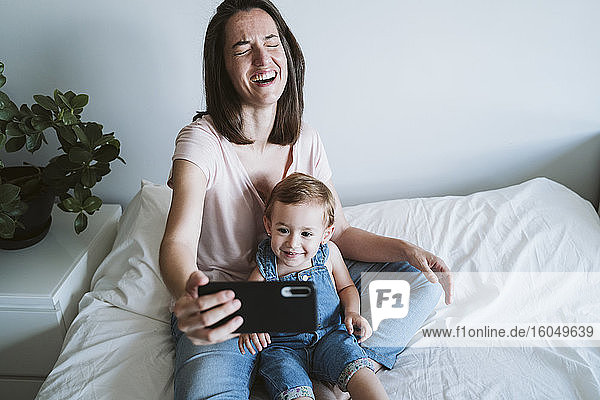 Mutter und kleines Mädchen machen ein Selfie mit Smartphone zu Hause