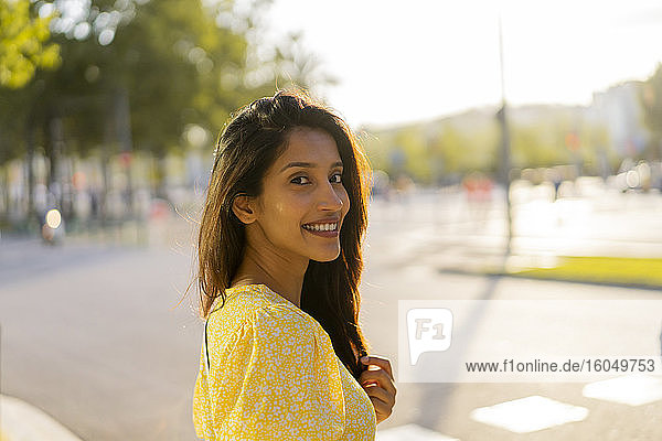 Schöne Frau lächelnd  während stehend auf Stadt Straße während sonnigen Tag