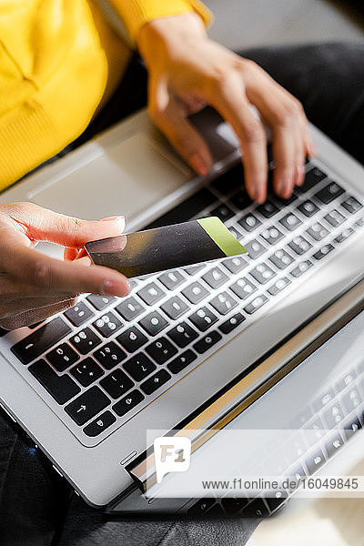 Woman's hand holding credit card while using laptop