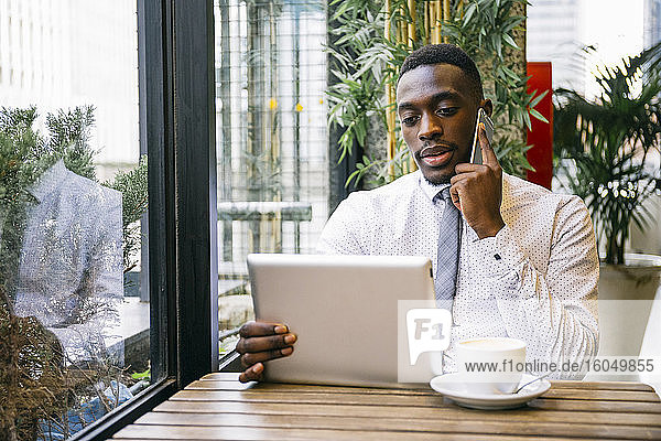 Young businessman using tablet and smartphone in a cafe