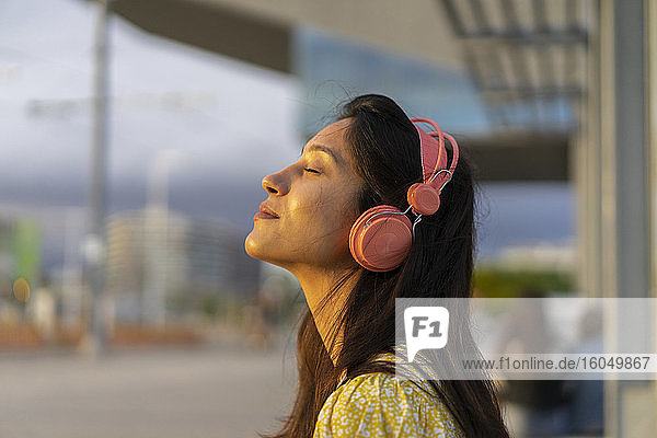Relaxed young woman listening music in city