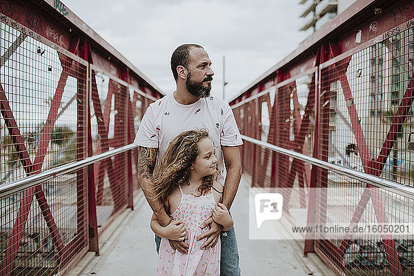 Vater und Tochter stehen auf einer Brücke in der Stadt