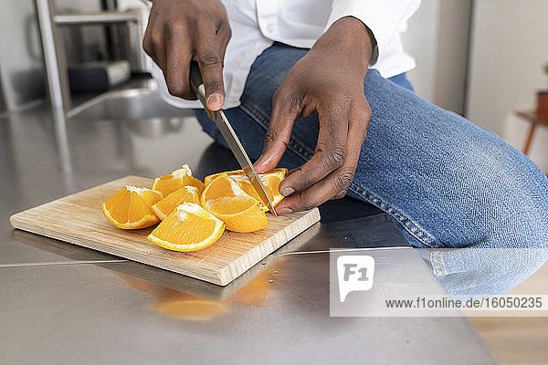 Männerhände  die eine Orange schneiden  Nahaufnahme