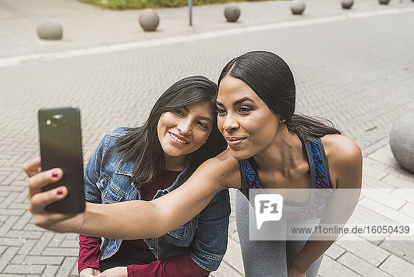 Young woman taking selfie with female friend