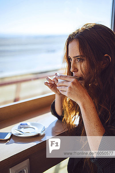 Thoughtful businesswoman drinking coffee at airport cafe