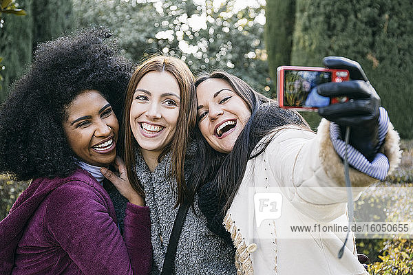 Fröhliche Freundinnen machen ein Selfie mit der Kamera  während sie im Park stehen