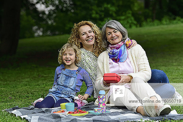 Cheerful three generation females enjoying picnic at public park