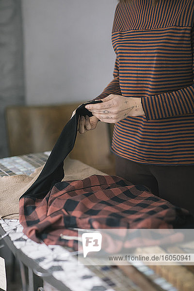 Nahaufnahme einer jungen Frau  die eine Platte auf einem Tisch in einem Atelier für Bekleidungsdesign hält