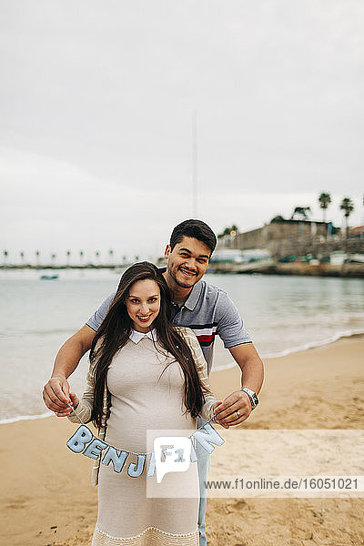 Glückliches schwangeres Paar mit Namensschild am Strand  Cascais  Portugal