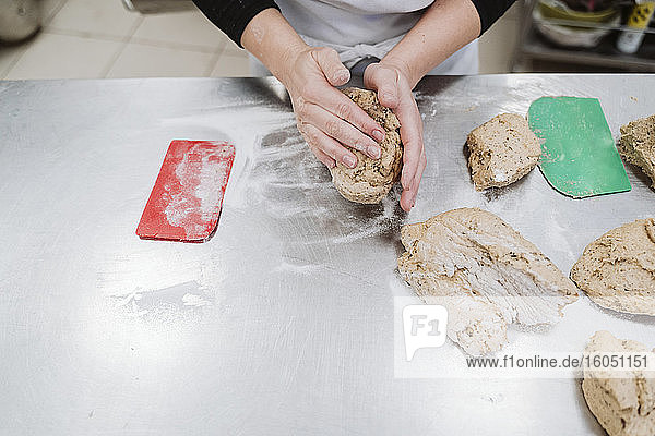 Bäckerin bei der Vorbereitung eines Brotlaibs auf dem Küchentisch in einer Bäckerei