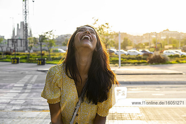 Fröhliche junge Frau auf der Straße in der Stadt an einem sonnigen Tag