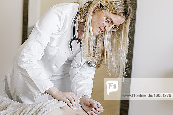 Akupunktur  Heilpraktikerin mit Akupunkturnadel während einer Behandlung am Rücken