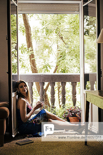 Woman enjoying coffee while sitting by balcony at home