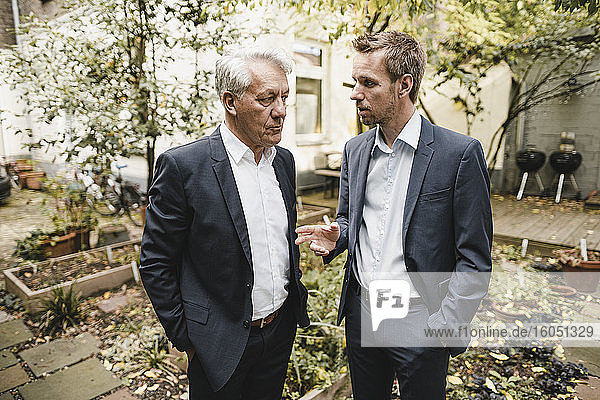Two businessmen standing office backyard  discussing
