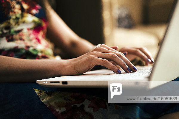 Close-up of woman's hands using laptop at home