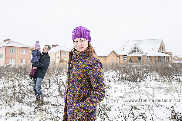 Beautiful woman with father and daughter in background during winter