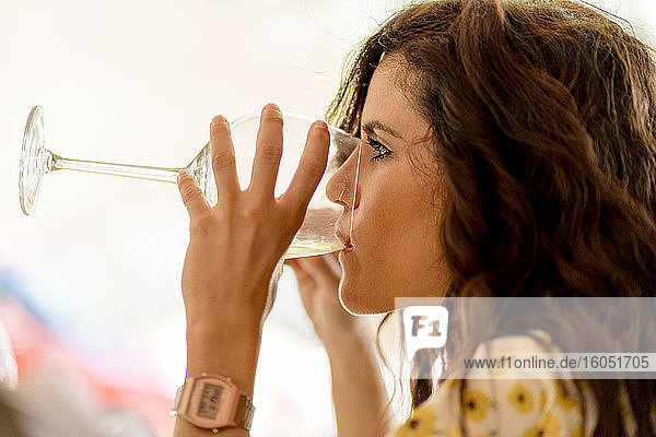 Junge Frau trinkt Weißwein  während sie im Restaurant sitzt
