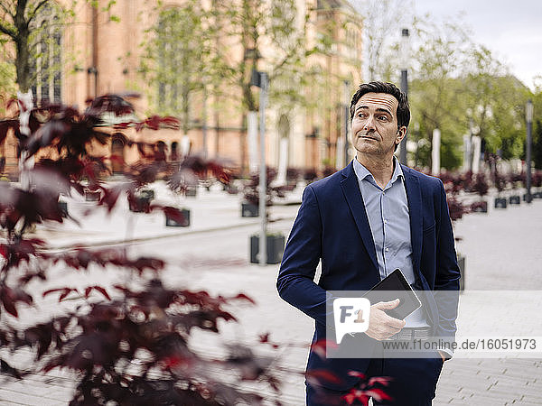 Mature businessman holding tablet in the city