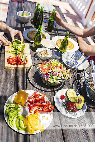 Brunch on table with male friends at building terrace during sunny day