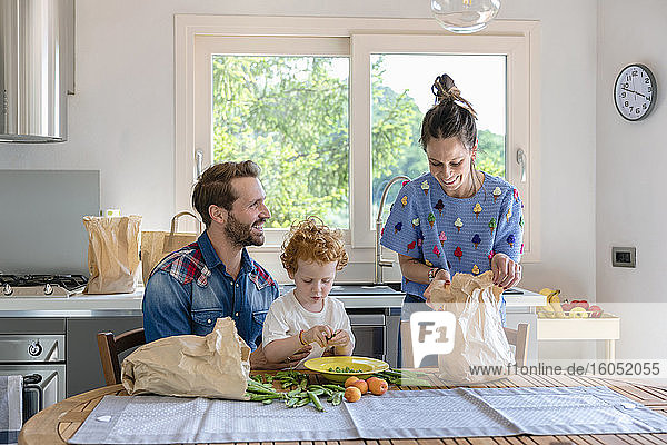 Boy with smiling parents in kitchen at home
