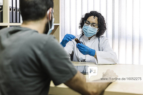 Weiblicher Arzt bespricht Medizin mit Patient im Büro in der Klinik