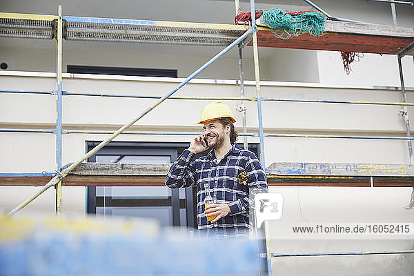 Lächelnder Arbeiter am Telefon auf einer Baustelle