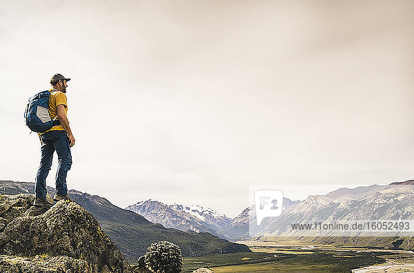 Male hiker with backpack standing on rock against sky at Patagonia  Argentina