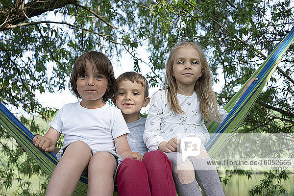 Niedliche Kinder sitzen auf Hängematte im Wald