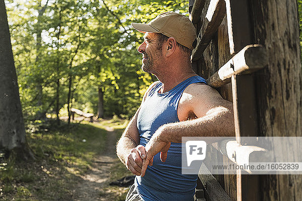 Nachdenklicher reifer Mann  der sich auf einer Holzleiter im Park abstützt