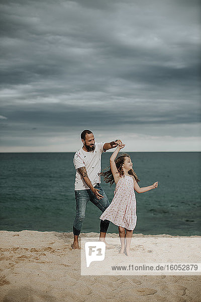 Glücklicher Vater und Tochter tanzen am Strand