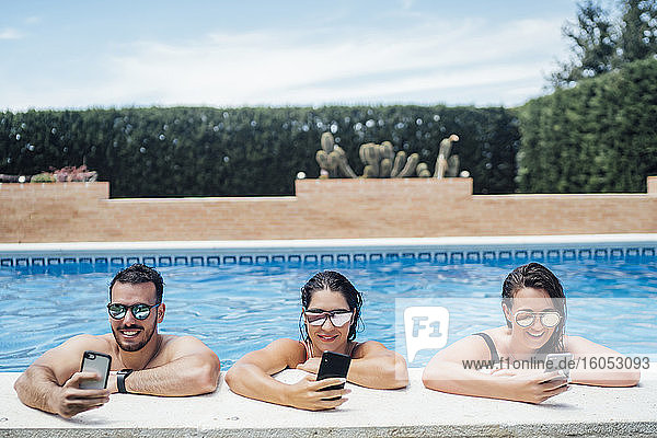 Freunde bei einer Poolparty mit Smartphones