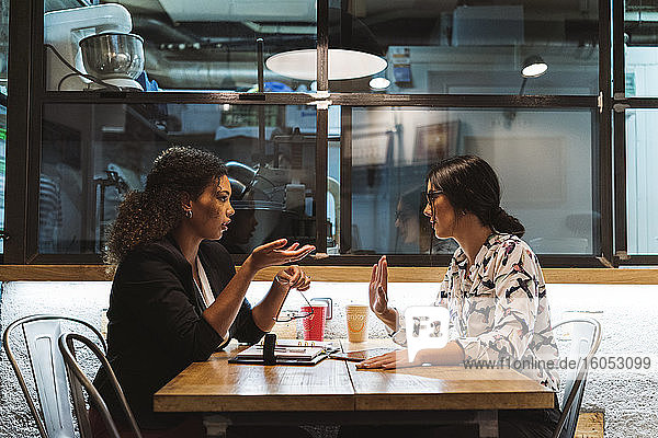 Weibliche Geschäftskollegen  die im Café sitzen und diskutieren