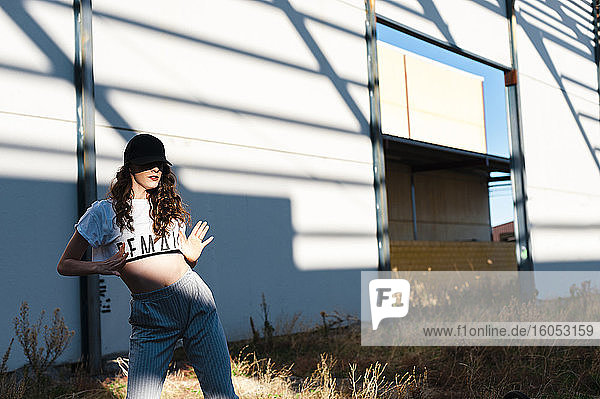 Hip-Hop-Tänzerin tanzt vor verlassenem Gebäude an einem sonnigen Tag