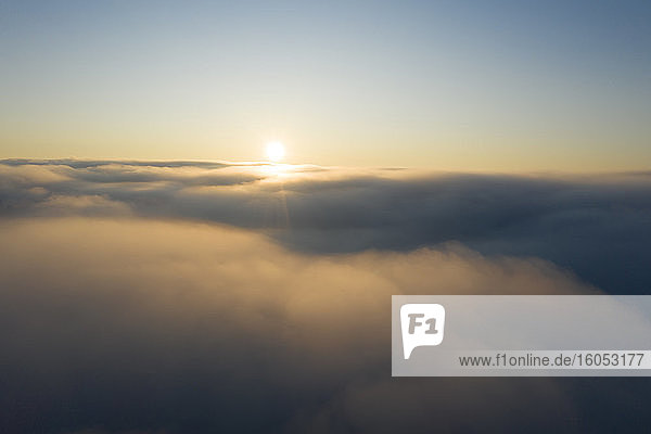 Drohnenansicht der aufgehenden Sonne über dichtem Nebel