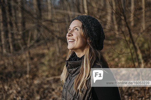Smiling mid adult woman looking up while standing in forest