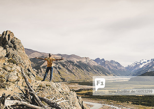 Male hiker with arms outstretched looking at Patagonia Andes while standing on rock  Argentina