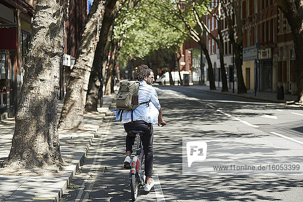 Rückansicht eines jungen Mannes  der mit einem Leihfahrrad auf einem Fahrradweg fährt  London  UK