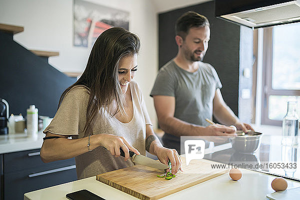 Ehepaar bei der Zubereitung von Speisen auf einer Kücheninsel zu Hause