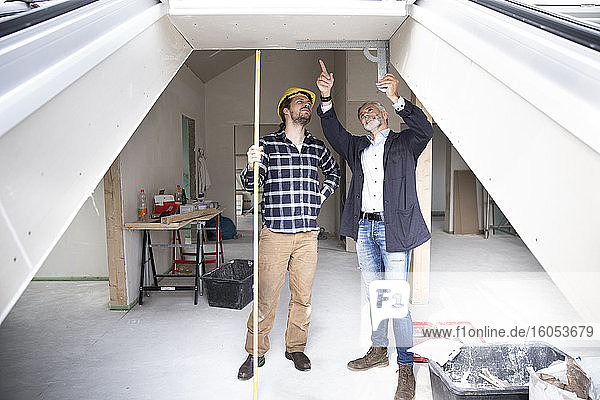 Architekt und Bauarbeiter diskutieren über den Rahmen bei der Renovierung eines Hauses  gesehen durch ein Fenster