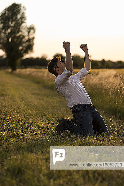 Mann tanzt auf einem Feld im Abendlicht