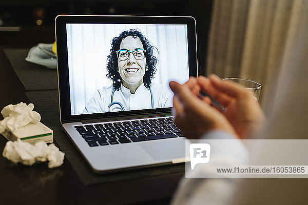 Kranke Frau im Ruhestand bespricht sich per Videoanruf mit einem lächelnden Arzt zu Hause