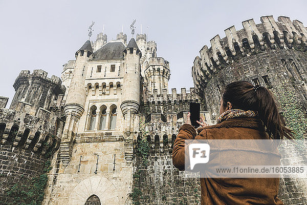 Frau fotografiert die Burg Butron mit ihrem Smartphone  Baskenland  Spanien