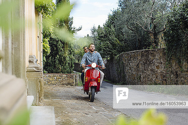 Man with girlfriend riding on Vespa