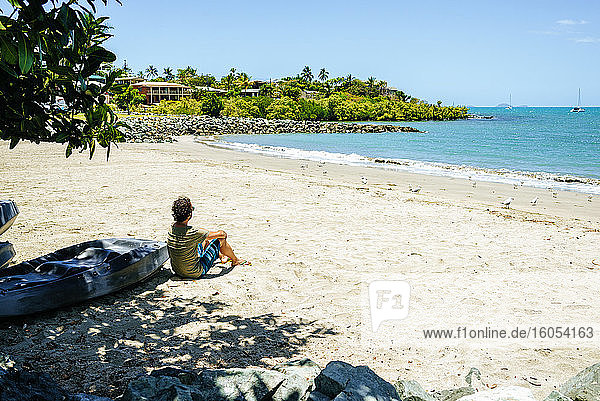 Mittlerer erwachsener Mann am Strand sitzend vor blauem Himmel an einem sonnigen Tag  Australien
