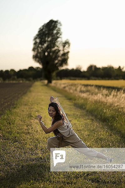Frau tanzt auf einem Feld am Abend