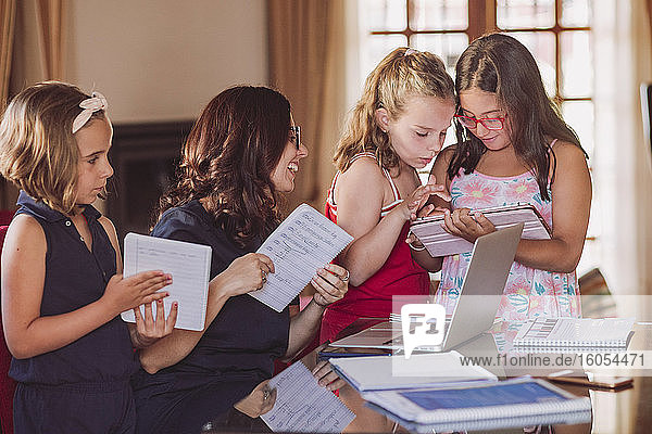 Smiling woman with daughters while working at home