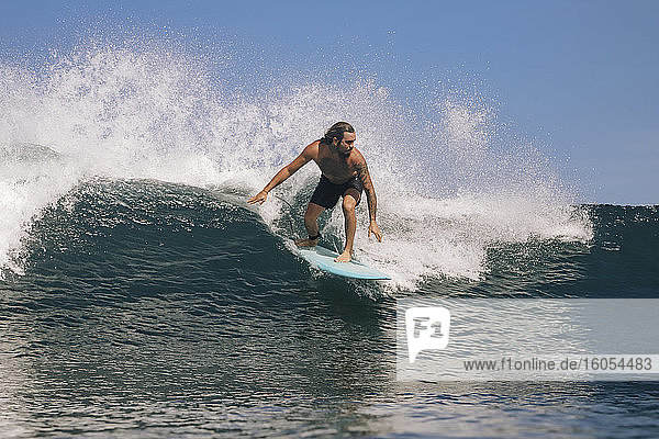 Mann ohne Hemd surft auf dem Meer gegen den klaren Himmel  Bali  Indonesien