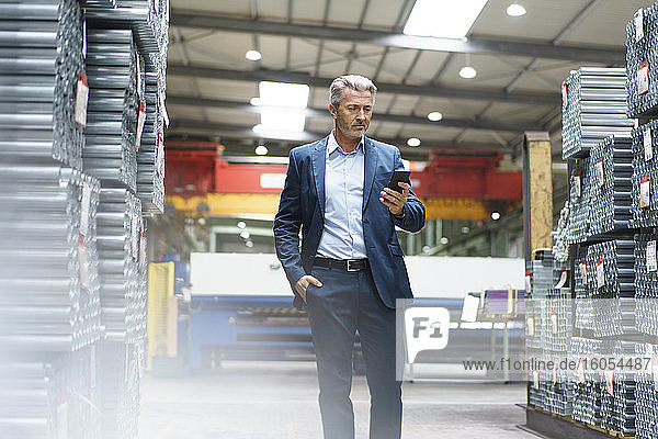 Mature businessman using mobile phone in a factory